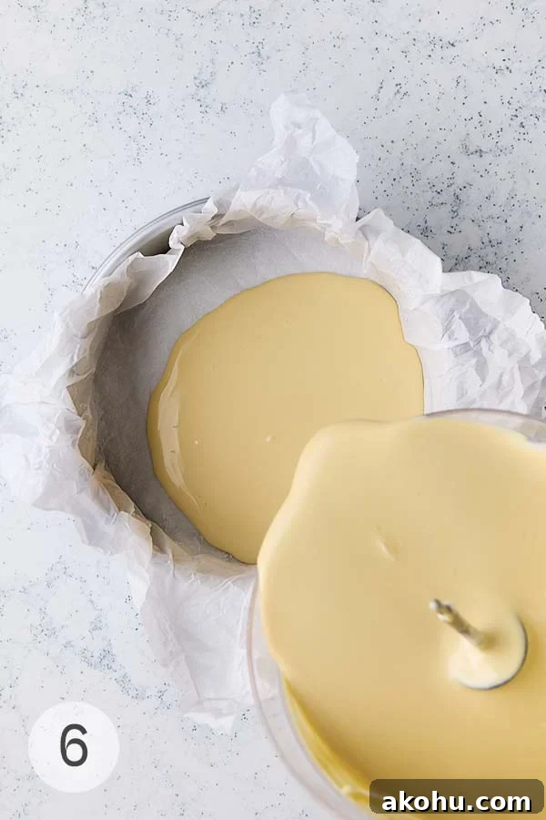 Basque Cheesecake with Tangy Pomegranate Molasses Glaze 12 The batter for a burnt Basque cheesecake being poured into a springform pan lined with parchment paper.