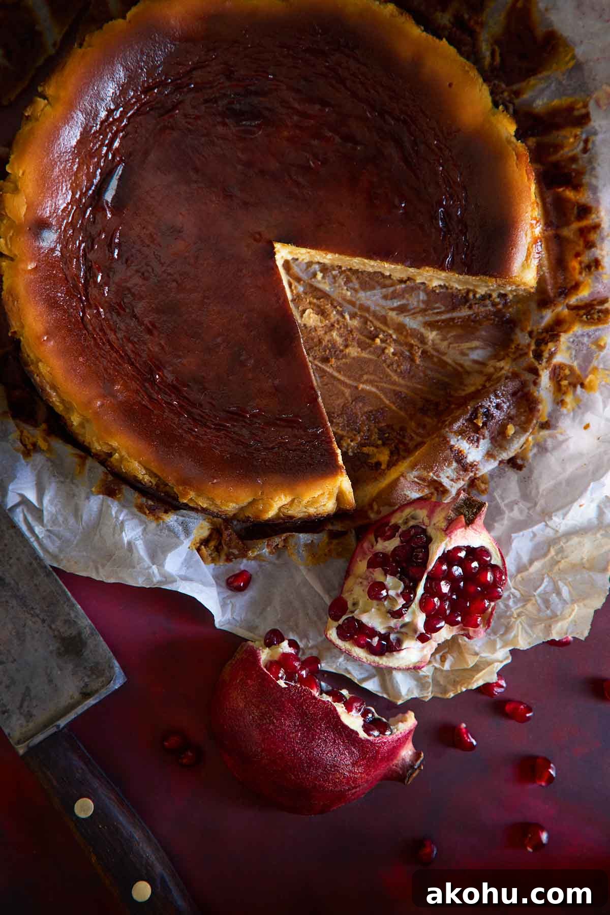 Basque Cheesecake with Tangy Pomegranate Molasses Glaze 13 An overhead shot of a Basque Cheesecake with pomegranate, with a slice taken out to reveal the creamy interior.