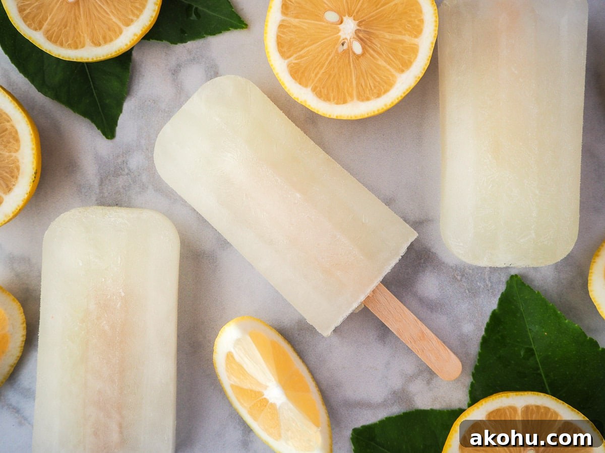 Lemonade popsicles surrounded by fresh lemon slices and lemon leaves.