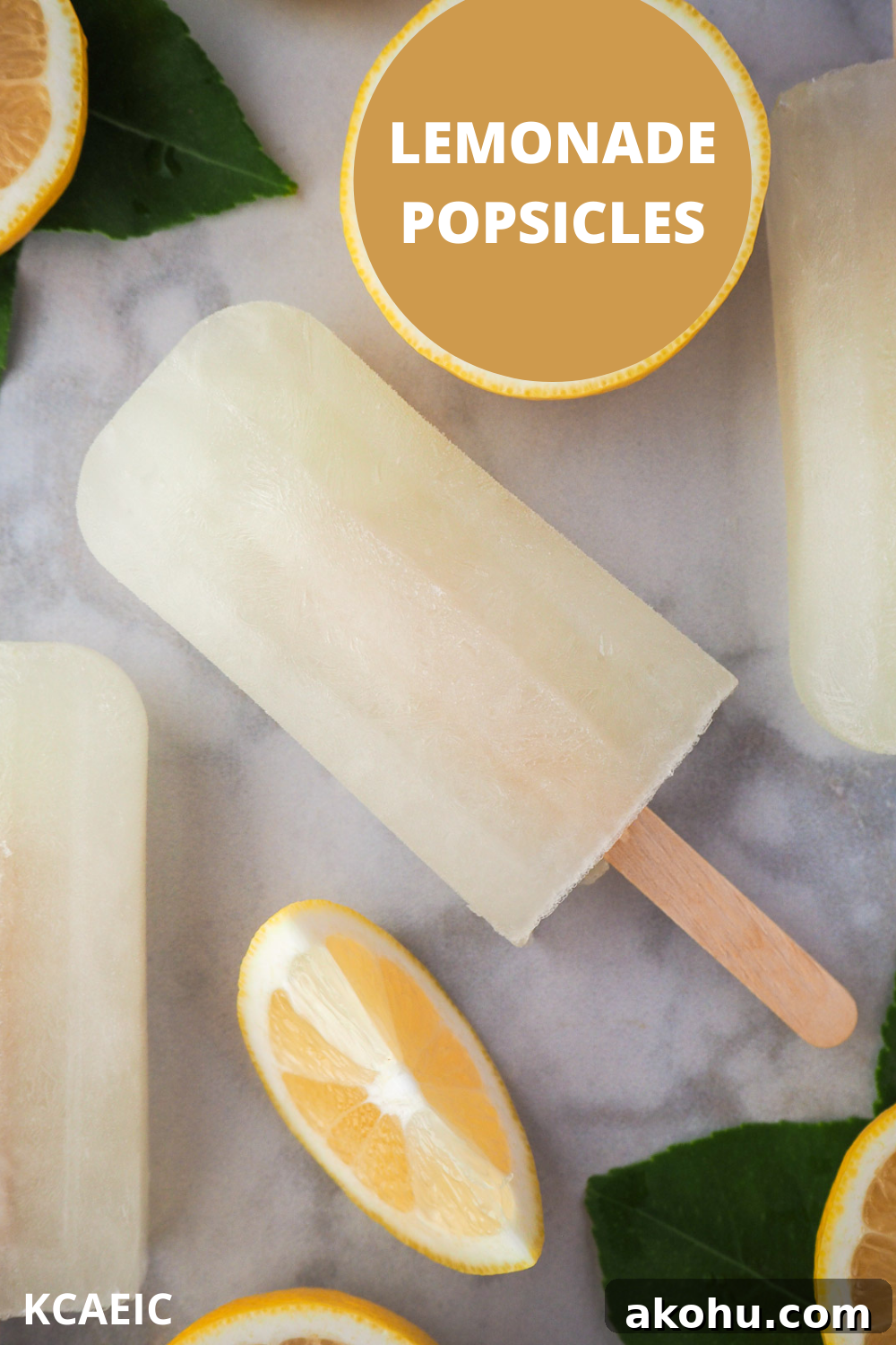 Close up of lemonade popsicles surrounded by fresh lemon slices and lemon leaves, with text overlay, Lemonade popsicles and KCAEIC.