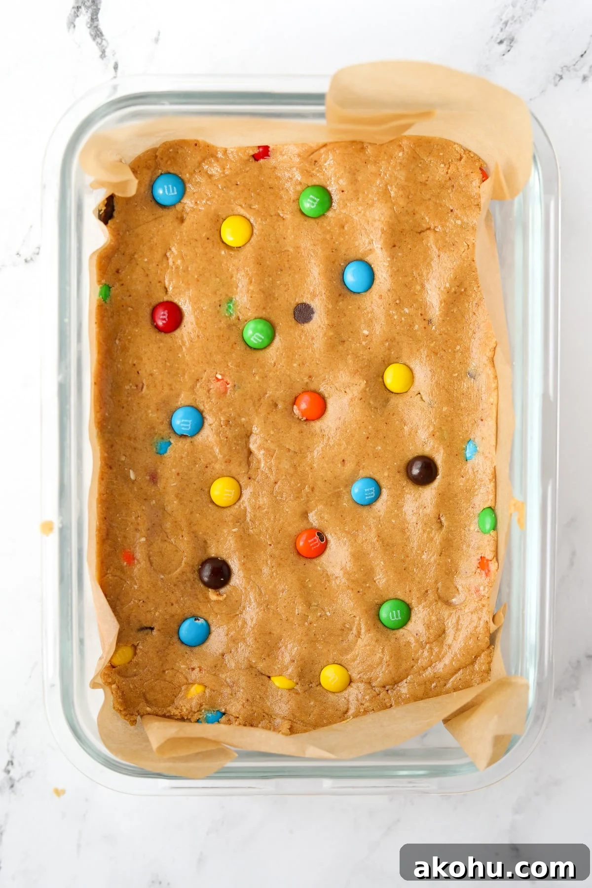 Monster Cookie Protein Bars: Chewy Peanut Butter Oat Bars 9 Protein dough pressed into a parchment lined baking dish.