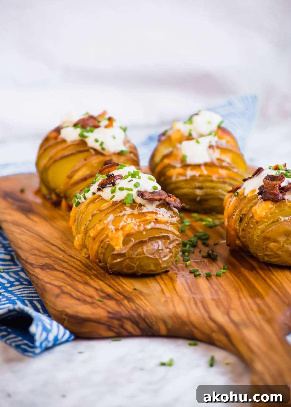 20 Delicious Side Dishes to Serve with Roasted Chicken 9 Bacon Cheddar Hasselback Potatoes on cutting board.