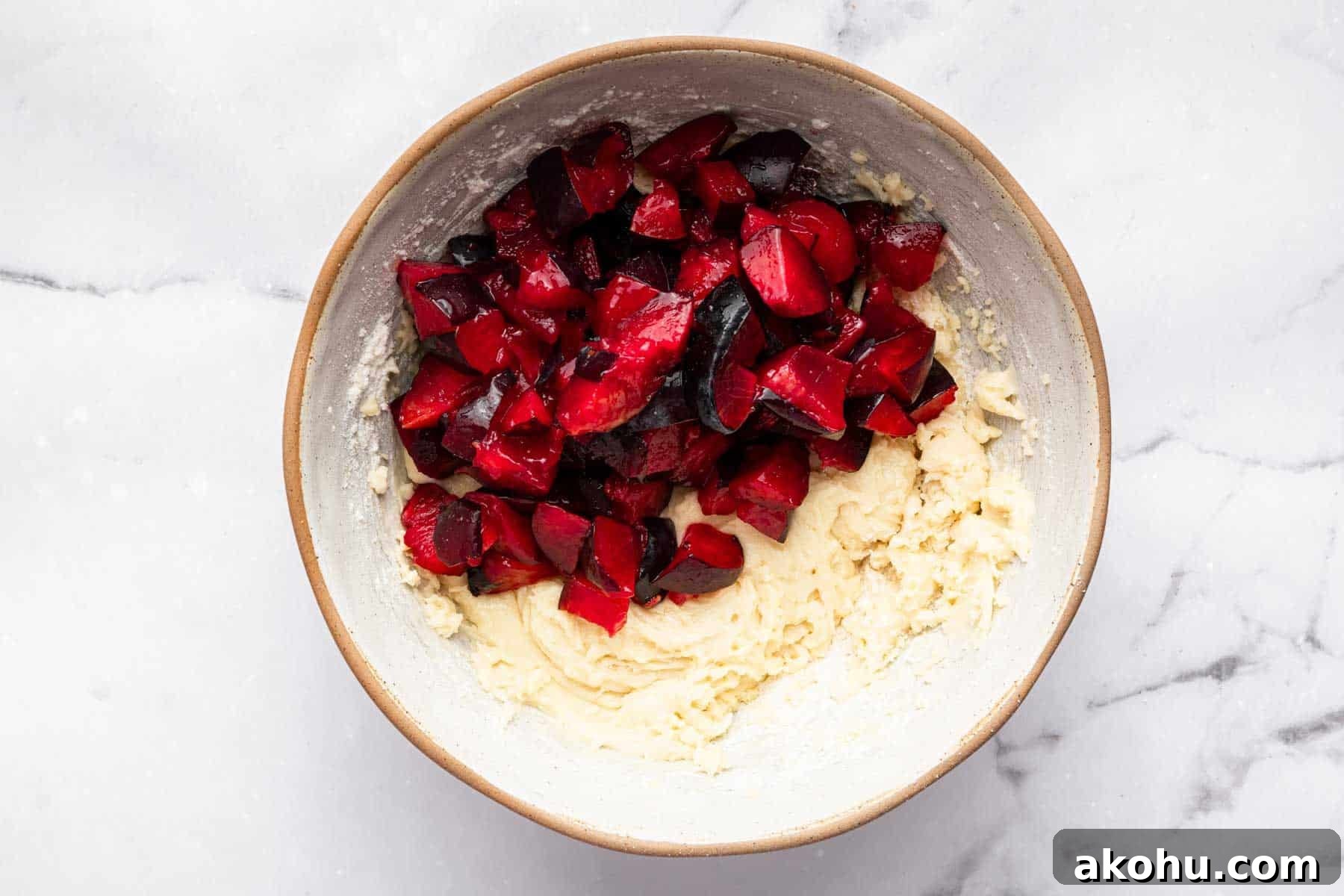 Classic Plum Cake Recipe: Moist, Fragrant Holiday Dessert 10 Yellow raw batter with diced red fruit on top.