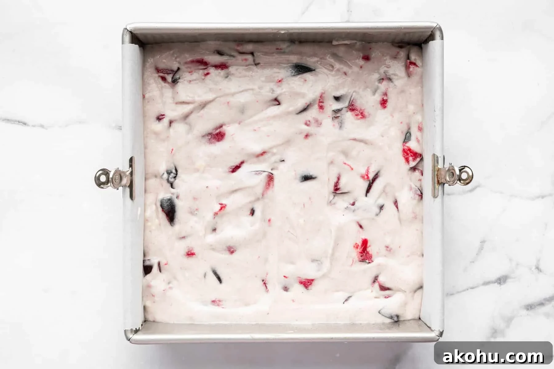Classic Plum Cake Recipe: Moist, Fragrant Holiday Dessert 11 White raw batter in a square pan with chunks of red and purple fruit.