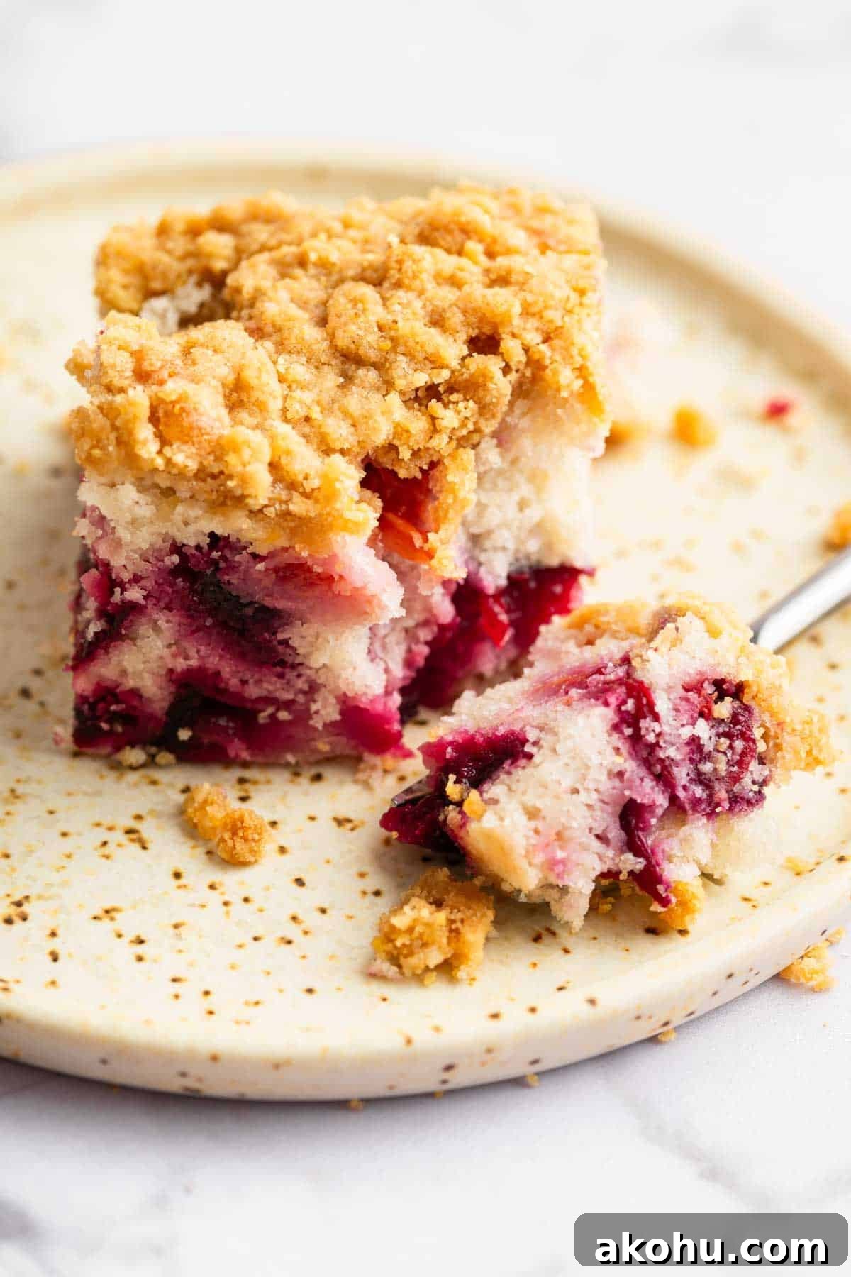 Classic Plum Cake Recipe: Moist, Fragrant Holiday Dessert 13 Square slice of plum cake on plate with fork removing a bite.
