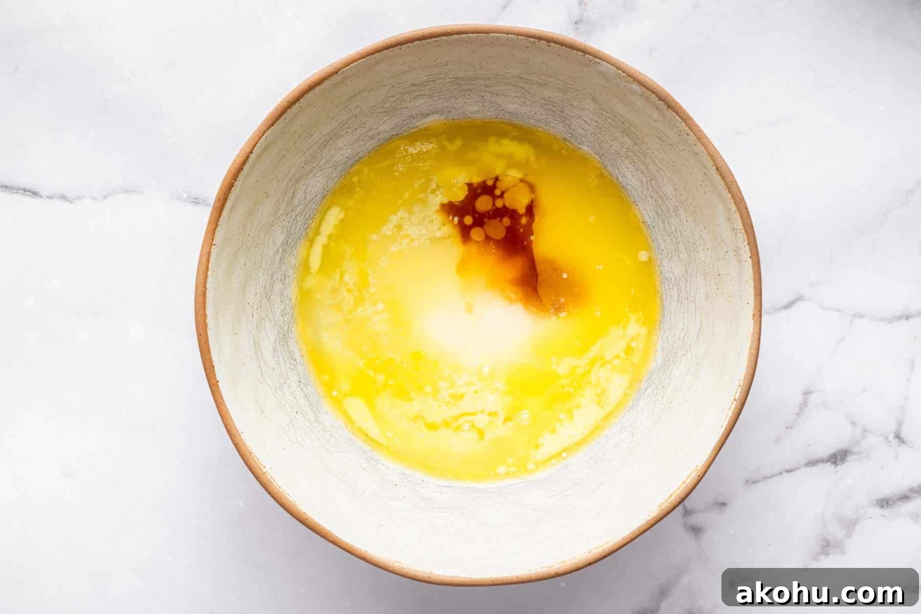 Classic Plum Cake Recipe: Moist, Fragrant Holiday Dessert 9 Mixing bowl with melted butter, sugar and a splash of brown vanilla.