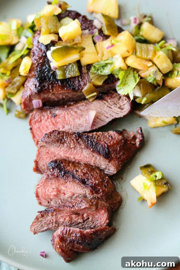 Grilled Steak with Pineapple Jalapeño Salsa Recipe 14 ancho Chile rubbed steak with grilled pineapple salsa on green plate with knife