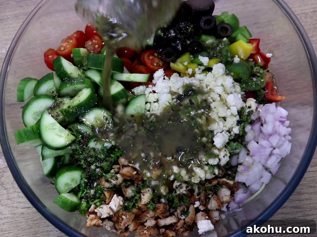 pouring mediterranean salad dressing on chicken spaghetti salad.