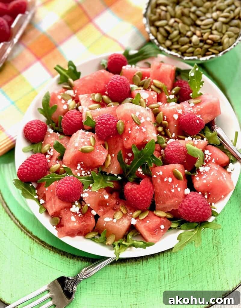 Watermelon, Arugula & Goat Cheese Salad with Balsamic Glaze 2 Watermelon salad garnished with arugula and goat cheese in white bowl.