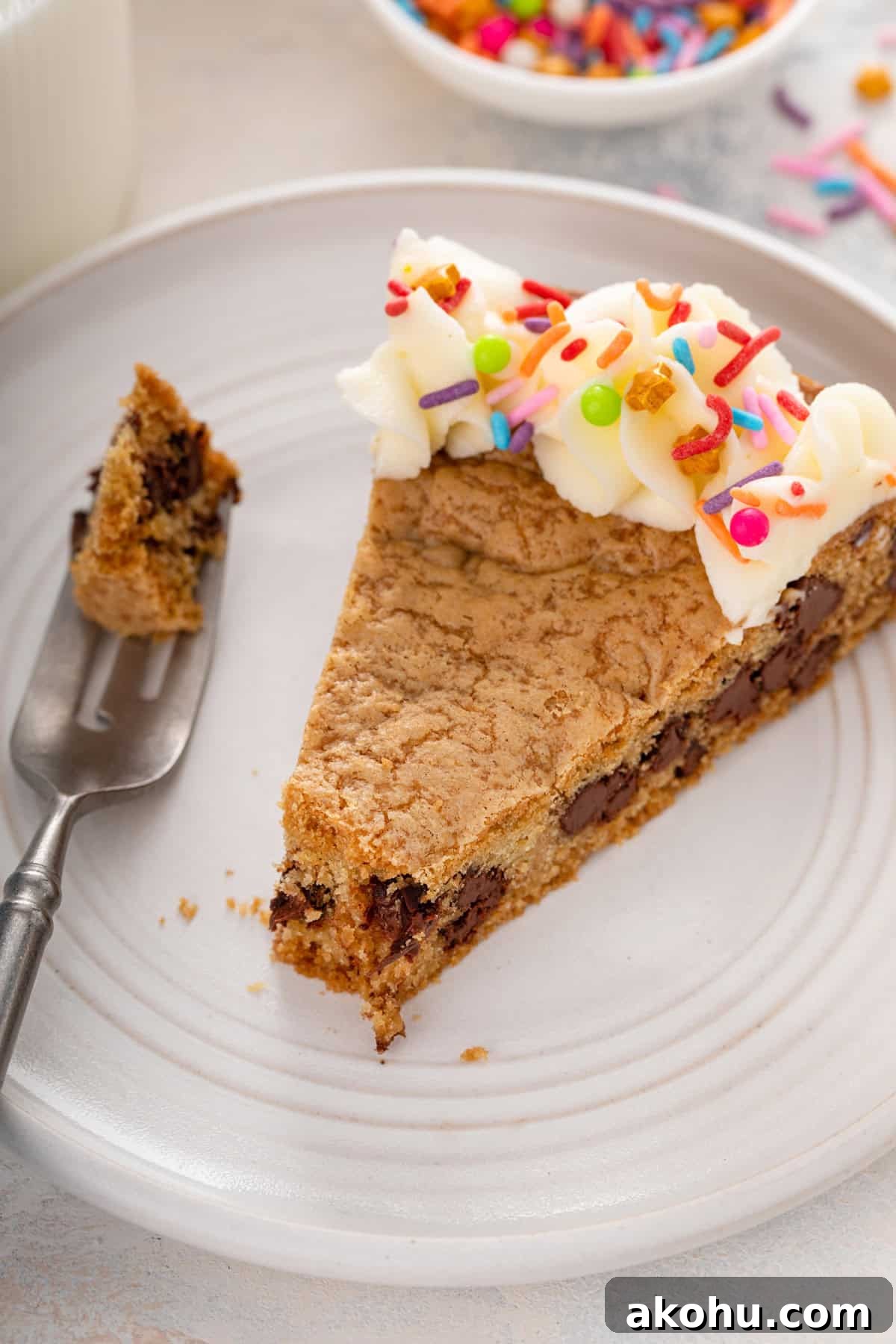 Chocolate Chip Cookie Cake Recipe — Soft, Gooey Dessert King 12 Plated slice of chocolate chip cookie cake with a bite cut from the end.