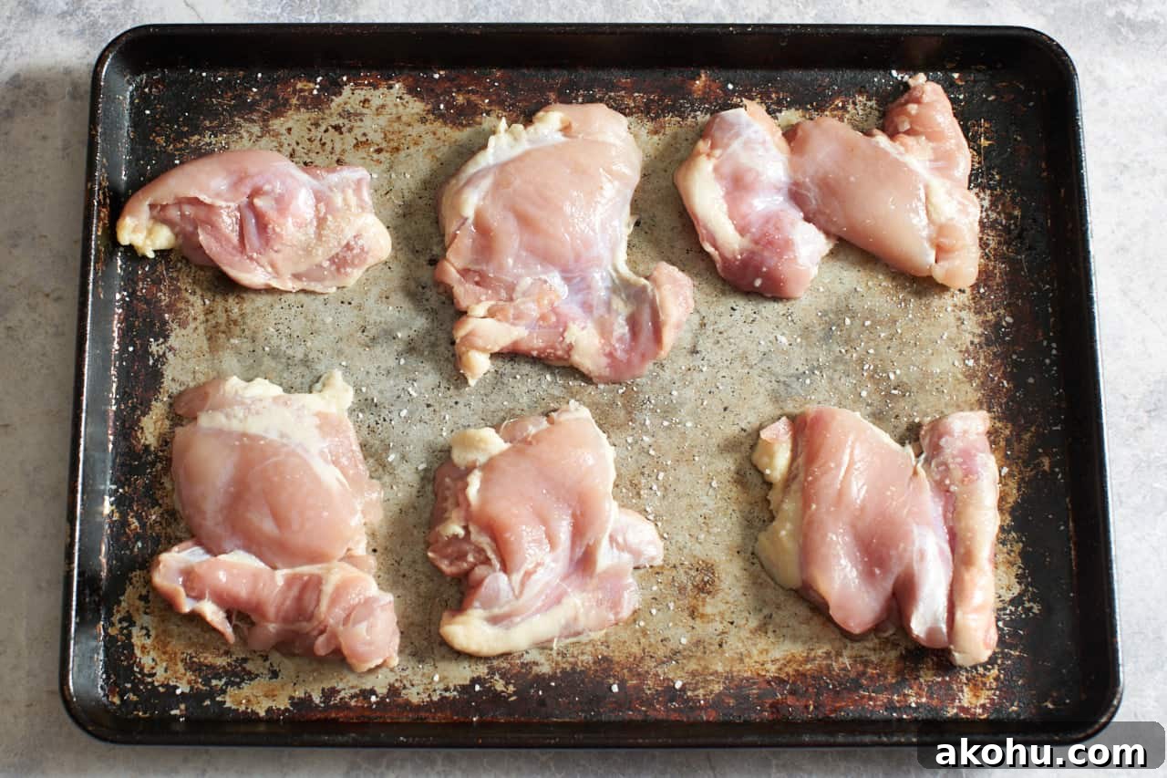 Salted chicken thighs on a sheet pan.