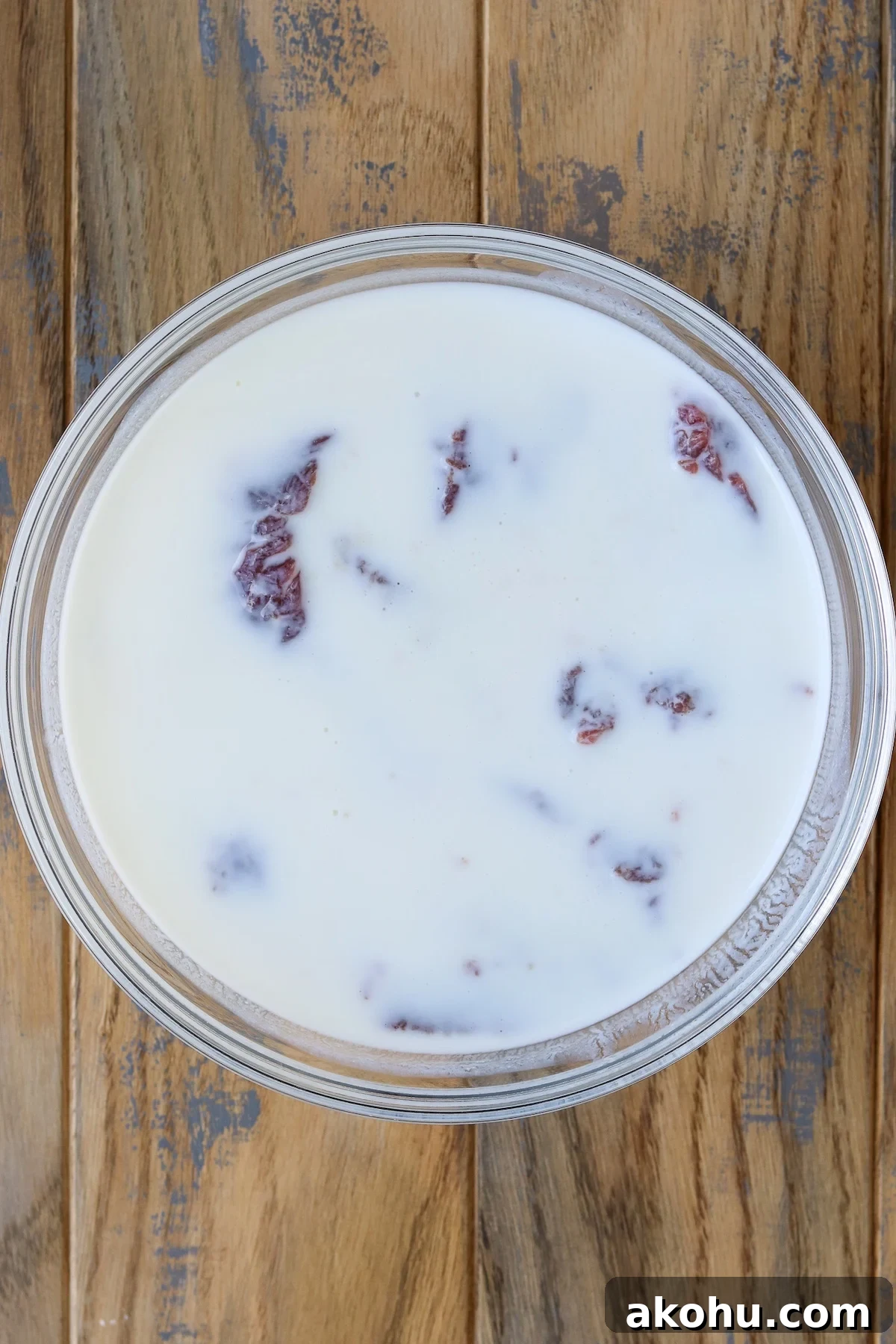 venison steak soaking in buttermilk in glass bowl