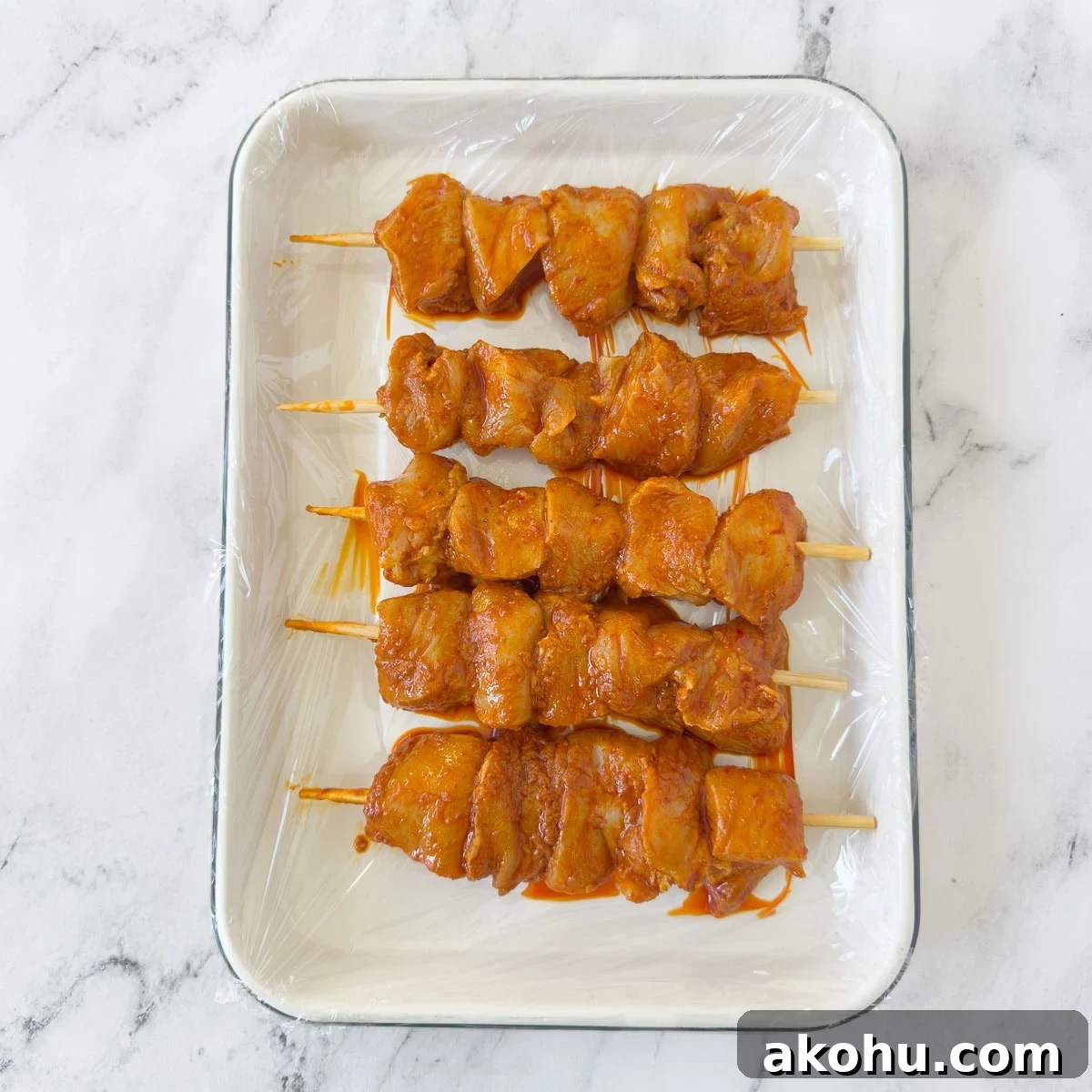 Harissa chicken chunks threaded onto bamboo skewers on a tray.