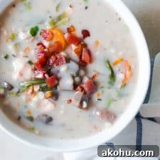 Creamy Slow Cooker Chicken Barley Soup topped with fried bacon and served in a white bowl.