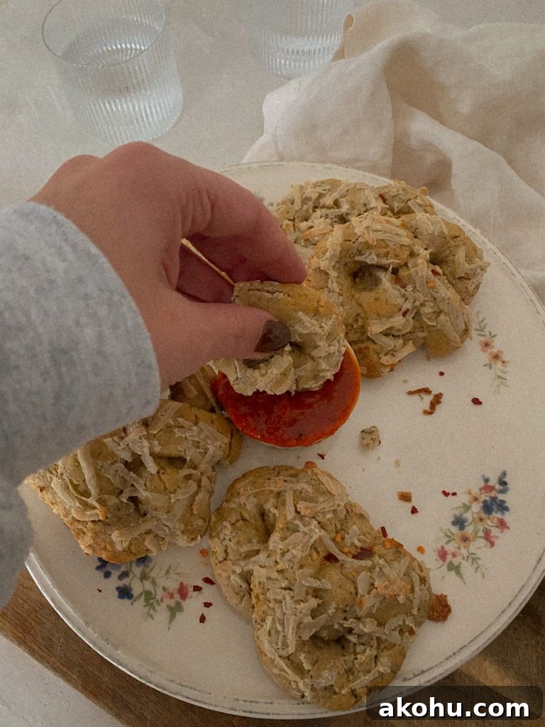 soft pizza pretzels on a white floral plate with hand dipping pretzel in a small bowl of marinara 