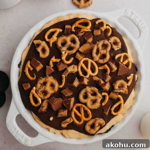 An overhead shot of a pie dish with a peanut butter pie covered in ganache and pretzels.