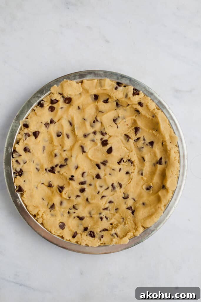 A pie plate with unbaked chocolate chip cookie crust