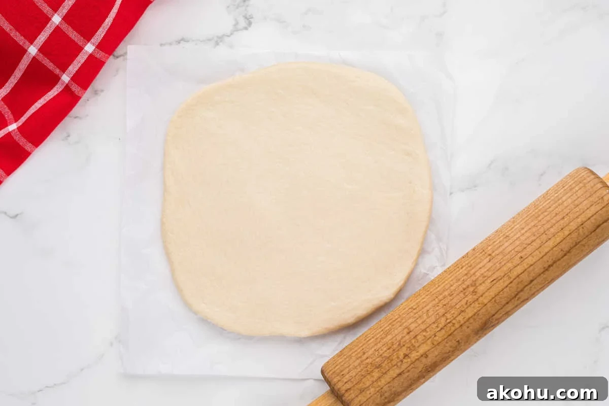 dough rolled out into circle with rolling pin beside.