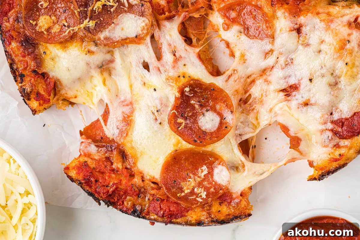 slice of pan pizza being lifted, showing a stringy, melted cheese.