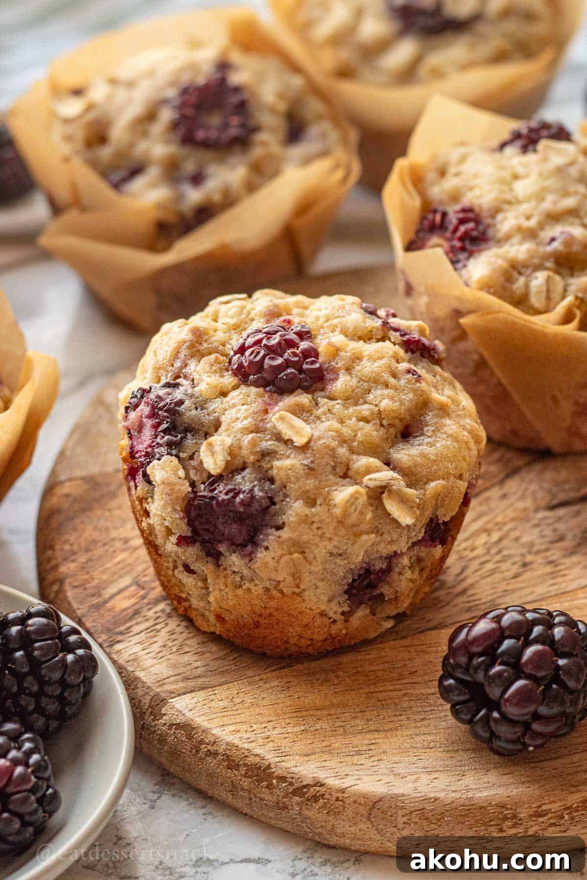 Banana Blackberry Oatmeal Muffins Recipe — Quick Baked Breakfast 2 Baked banana blackberry oatmeal muffin on wood cutting board with blackberries.