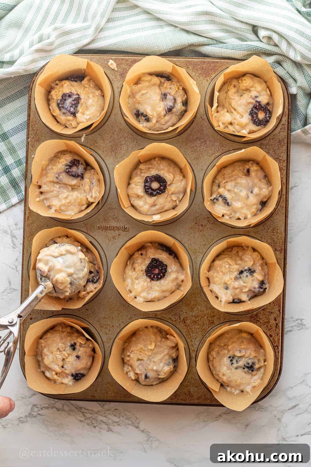 Banana Blackberry Oatmeal Muffins Recipe — Quick Baked Breakfast 9 Scooping raw banana blackbery oat muffin batter into muffin tin.