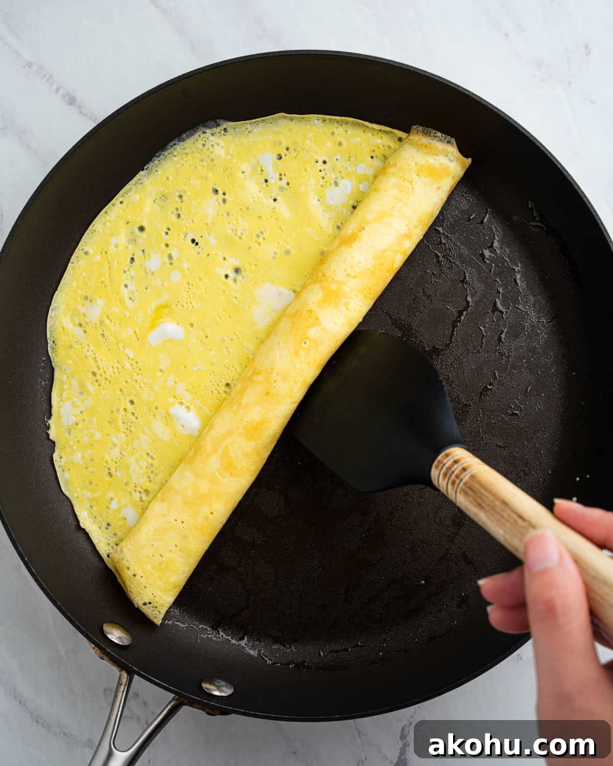 rolling up omelette in pan.