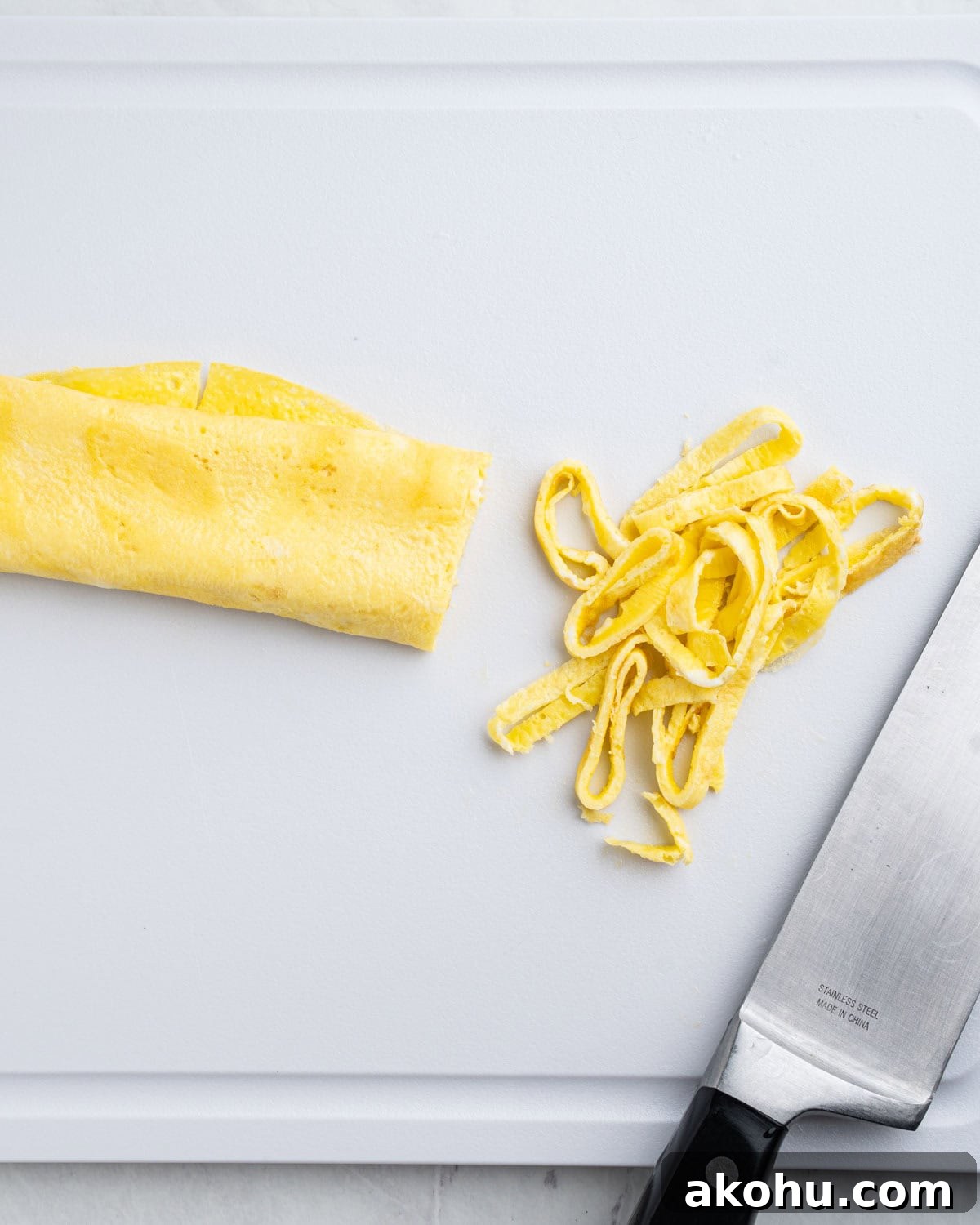 cutting rolled up omelette into strips on cutting board.