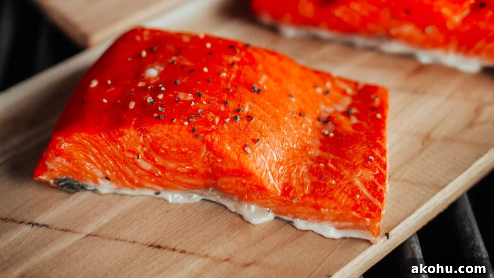 Smoked cedar plank salmon with rich smoky color and lemon slices resting on the plank.