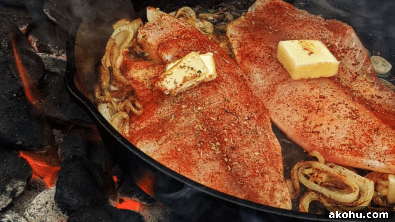 Tilapia grilled over charcoal with dark grill marks and lemon wedges beside it.