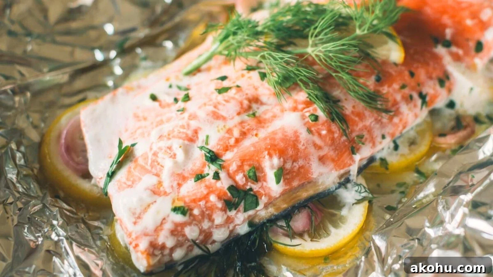 Grilled salmon cooked in foil with lemon slices and herbs wrapped around the fillet.