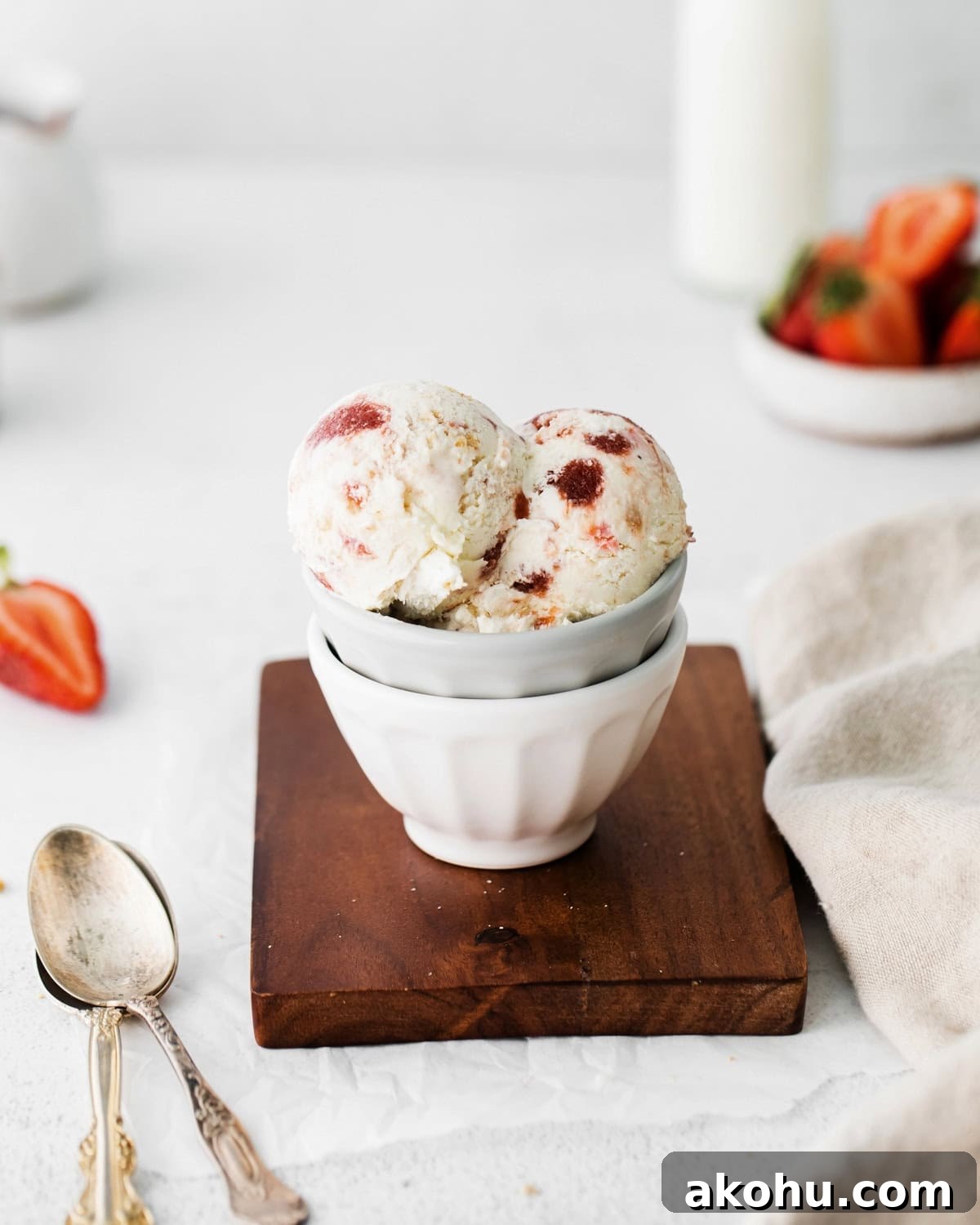 Scoops of homemade strawberry cheesecake ice cream served in a bowl next to two spoons.