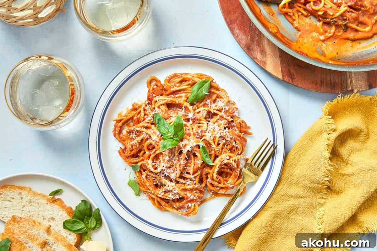 Final creamy tomato pasta plated with fresh basil, grated Parmesan, and olive oil drizzle ready to serve.