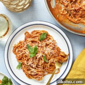 Plate of creamy tomato pasta with fresh basil and parmesan served in a white dish.