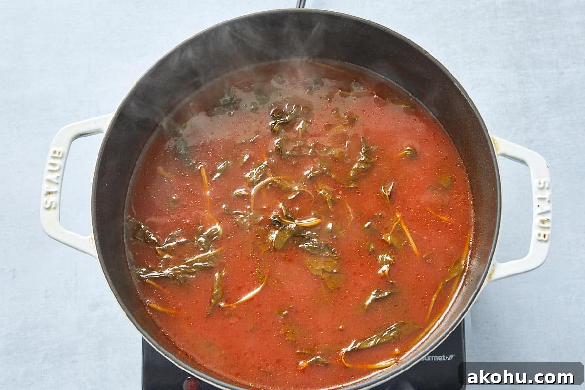 Simmering the tomato with water, salt, olive oil, parsley, and basil for the creamy tomato pasta base.