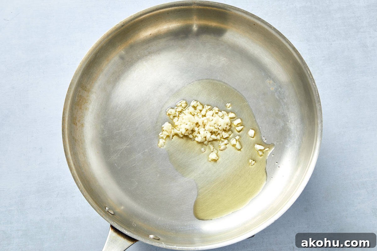 Garlic sizzling in olive oil in a pan, the first step in building flavor for creamy tomato pasta.