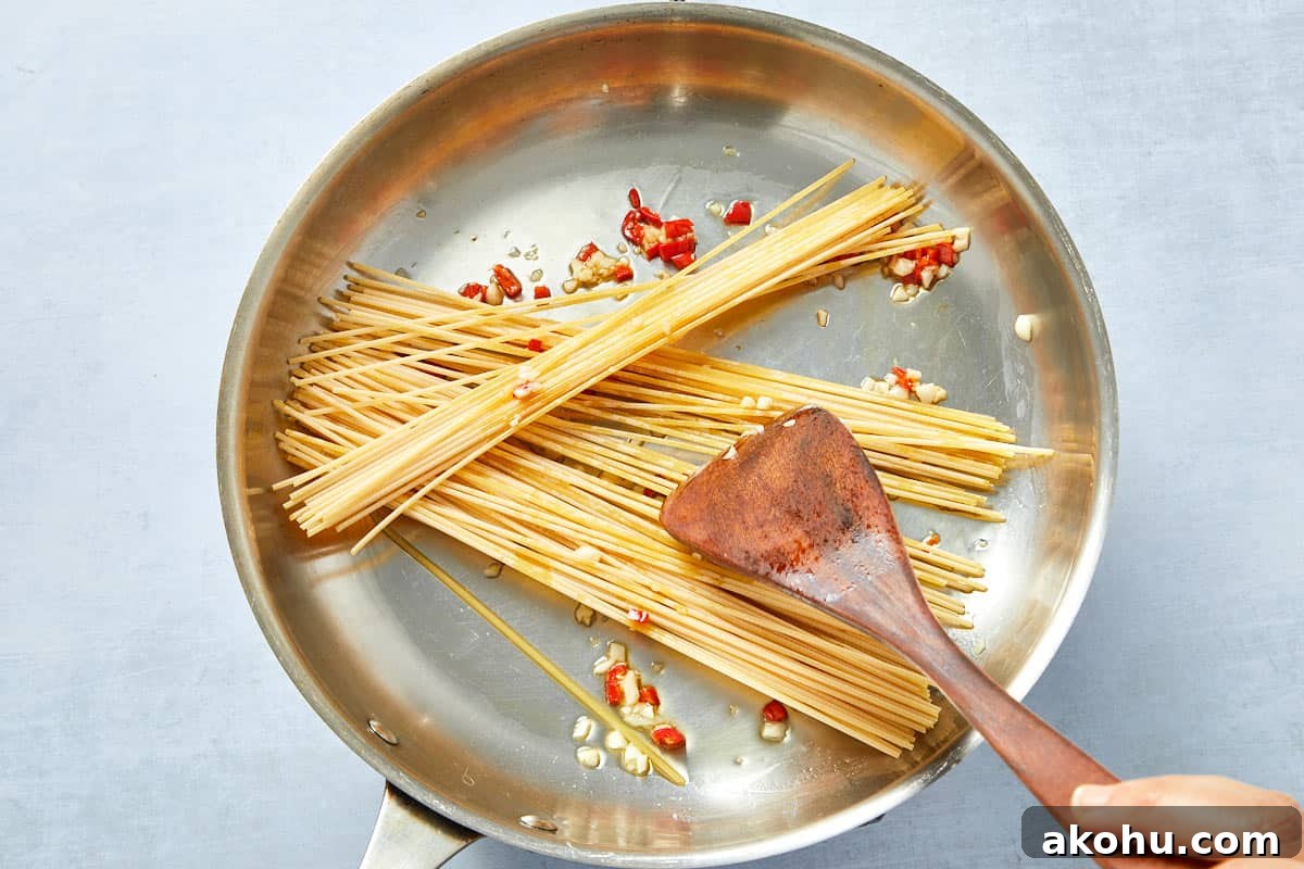 Dry spaghetti added to the garlic and chili oil.