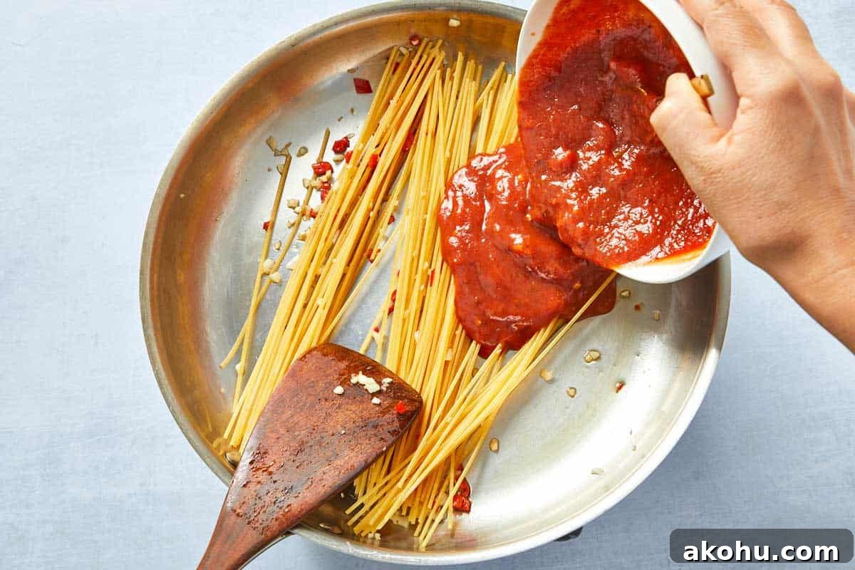 Pomodoro sauce poured over pasta in the pan.