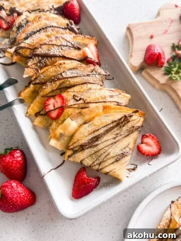 Strawberry Nutella crepes stacked on a plate.