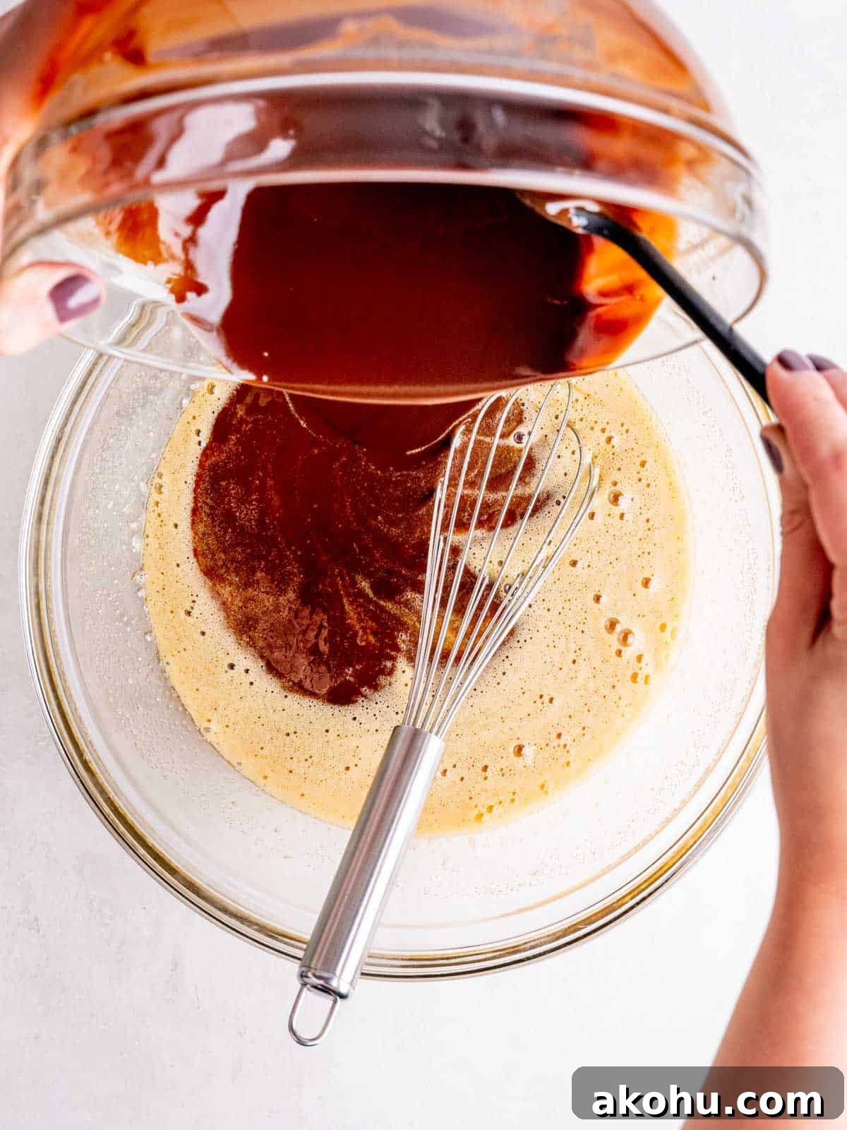 Decadent Andes Mint Brownies Recipe for Mint-Chocolate Lovers 5 Pouring a melted chocolate mixture into a bowl of whisked eggs and sugars.