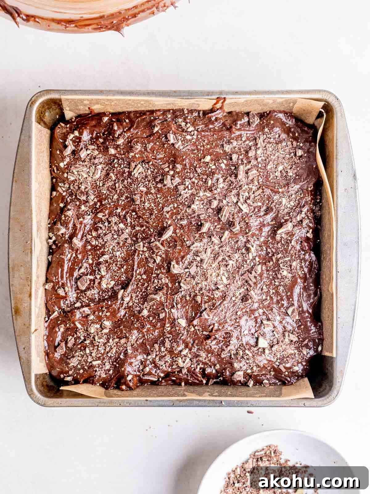 Decadent Andes Mint Brownies Recipe for Mint-Chocolate Lovers 8 Mint chocolate brownie batter in a parchment lined pan with Andes mint pieces on top.