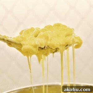 Creamy Instant Pot Macaroni and Cheese Recipe 13 holding a spoon of mac and cheese above an instant pot.