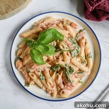 boursin cheese pasta on a plate, topped with sprig of basil.