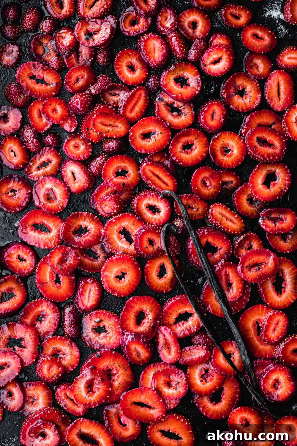 sliced strawberries with sugar, salt and vanilla beans on a baking sheet