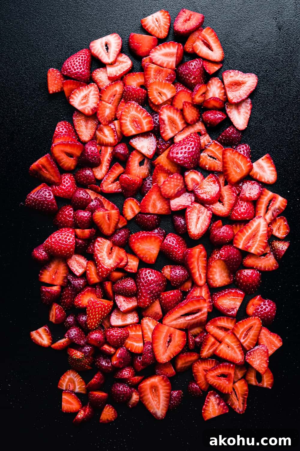 strawberry slices on a black cutting board