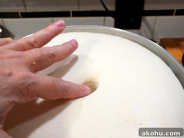 Finger being stuck into dough to show that it has risen.
