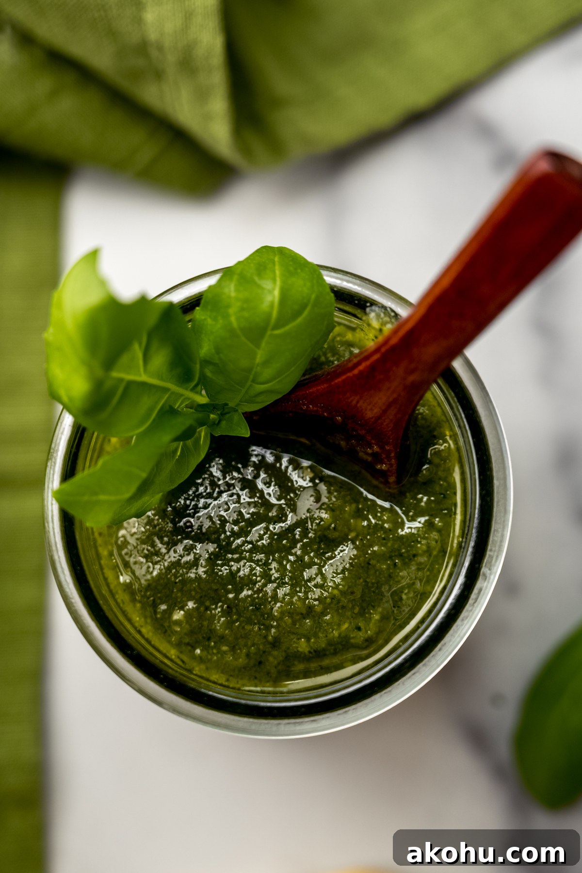 A jar of homemade pesto with a small wooden spoon in it.