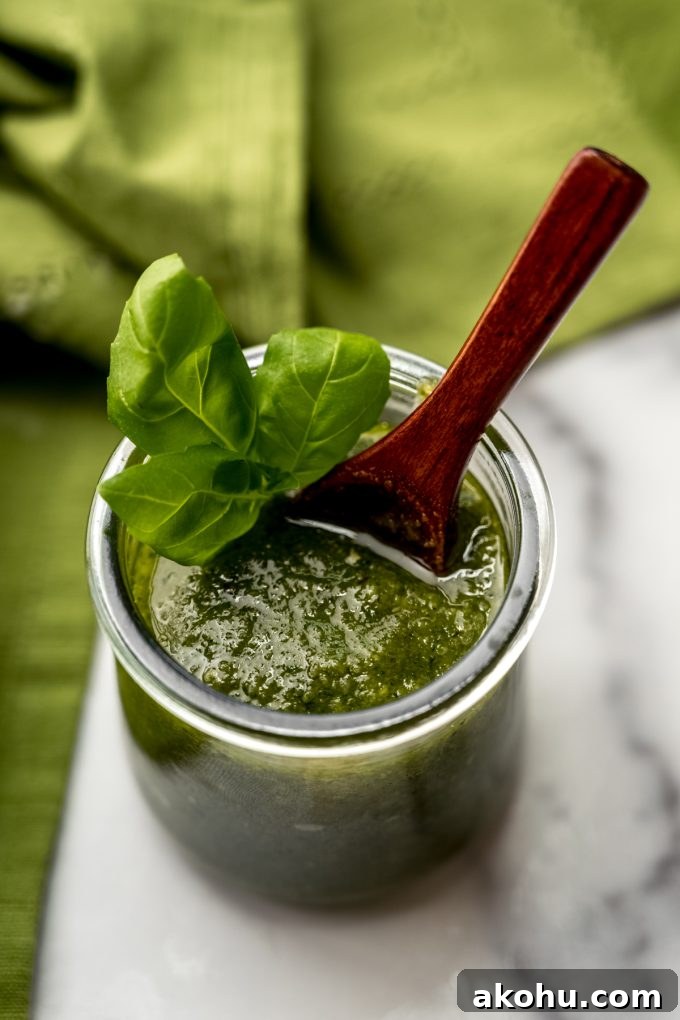A jar of homemade pesto with a small wooden spoon in it.