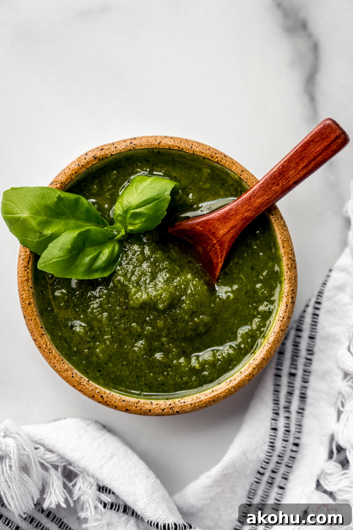 A bowl of homemade pesto with a small wooden spoon in it.