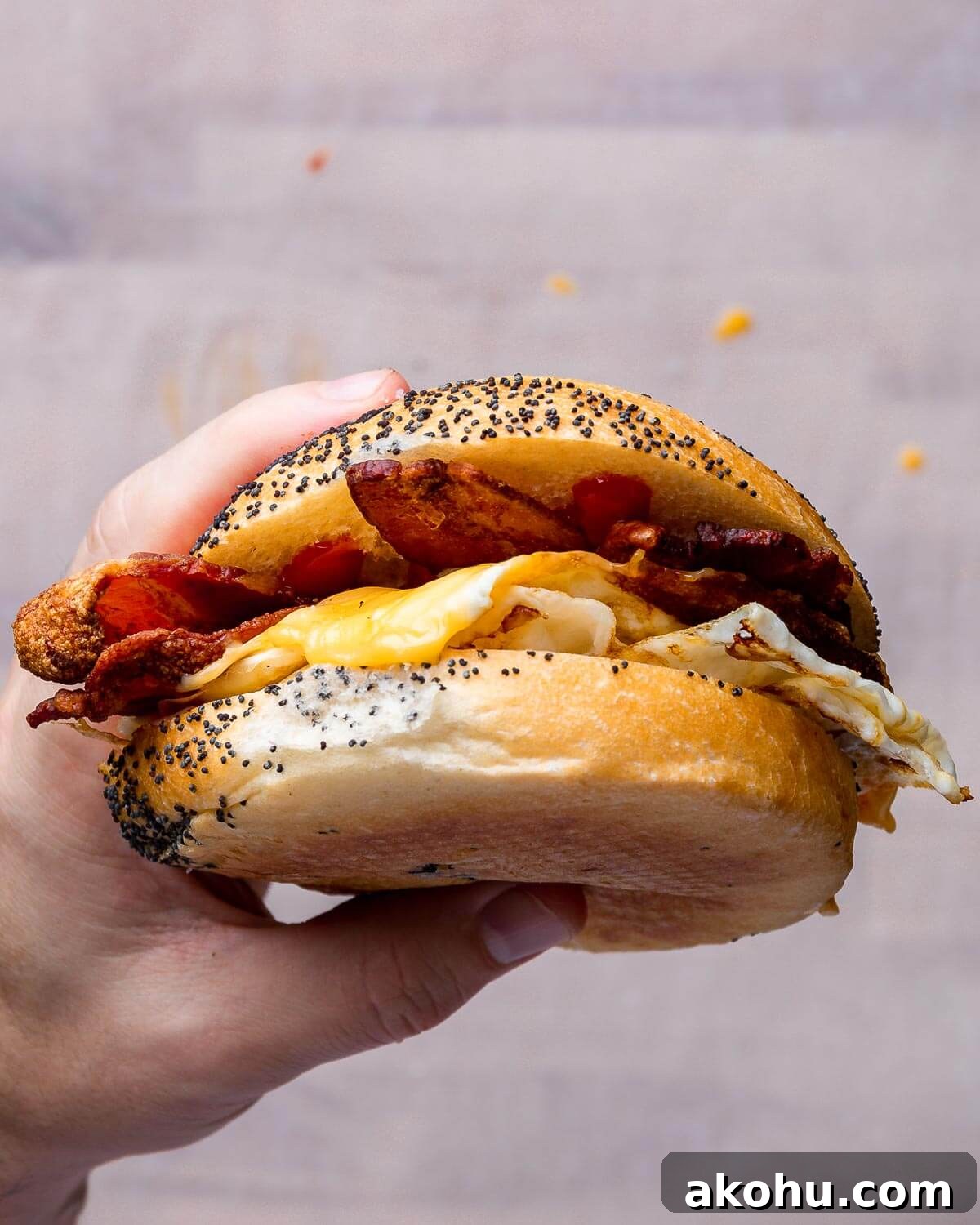Hand holding a cooked bacon egg and cheese sandwich.
