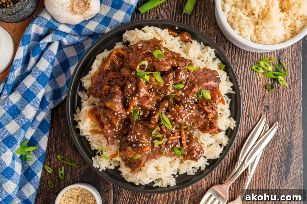 Slow Cooker Mongolian Beef Recipe — Tender Garlic Soy Beef 11 overhead of serving of slow cooker mongolian beef over rice.
